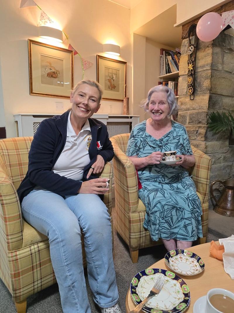 resident and carer sat in armchairs together smiling