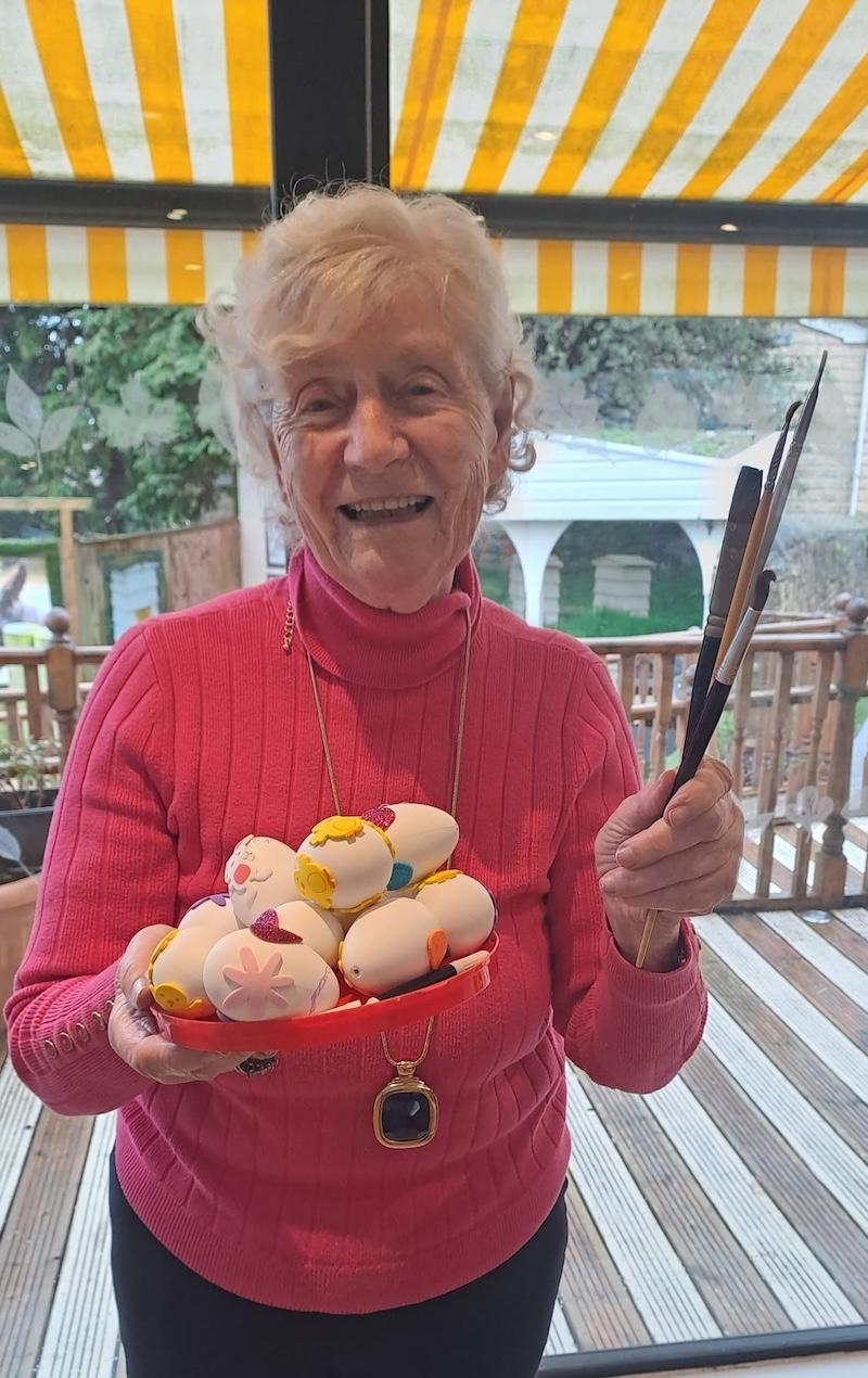 resident with a basket of eggs in her hand after decorating them