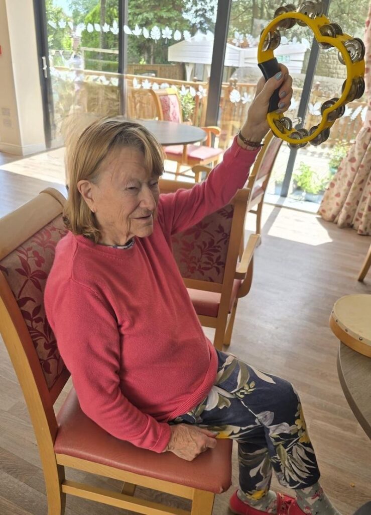 female resident holding a tambourine in the air smiling