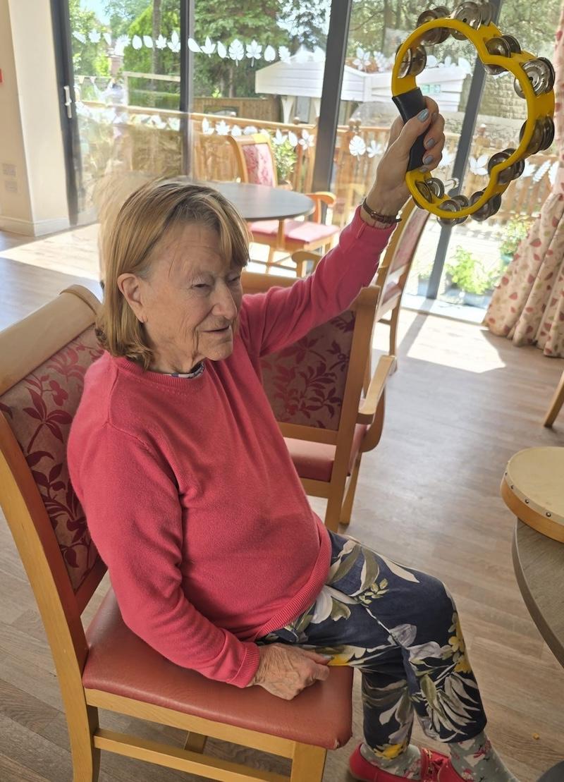 female resident holding a tambourine in the air smiling